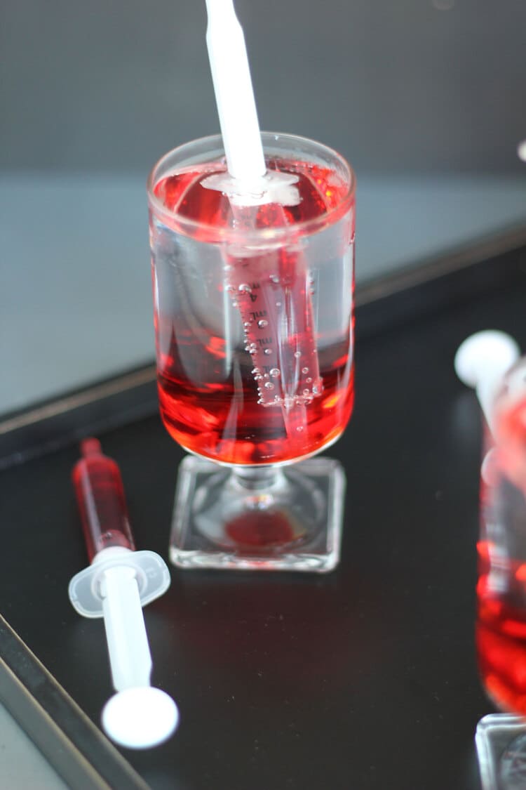 Up close photo of Shirley Temple drink in a glass with a syringe placed in it